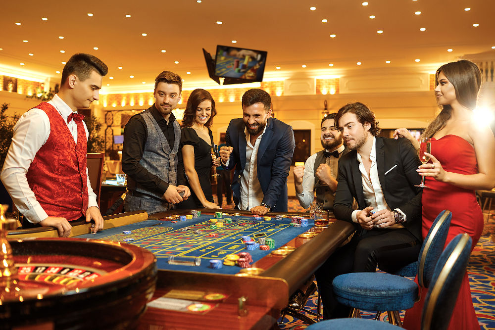 group happy people make bets gambiling at the roulette table in